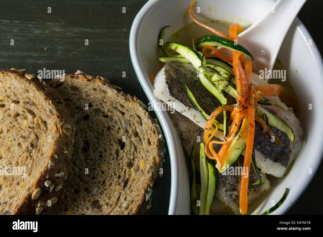 Nasello in brodo con la carota e la zucchina su sfondo scuro Foto Stock