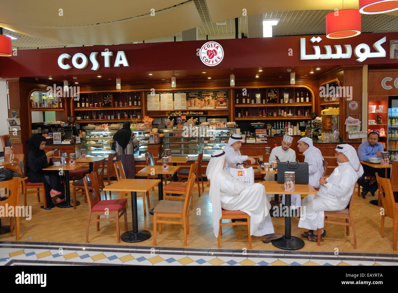 Avente uno snack a livello internazionale la catena di caffè Costa prima di salire a bordo del volo. Alla sala partenze dell'Aeroporto Internazionale di Bahrain. Il Bahrein ha una popolazione di oltre il 55% degli immigrati e aveva un'elezione generale in questo giorno. Foto Stock