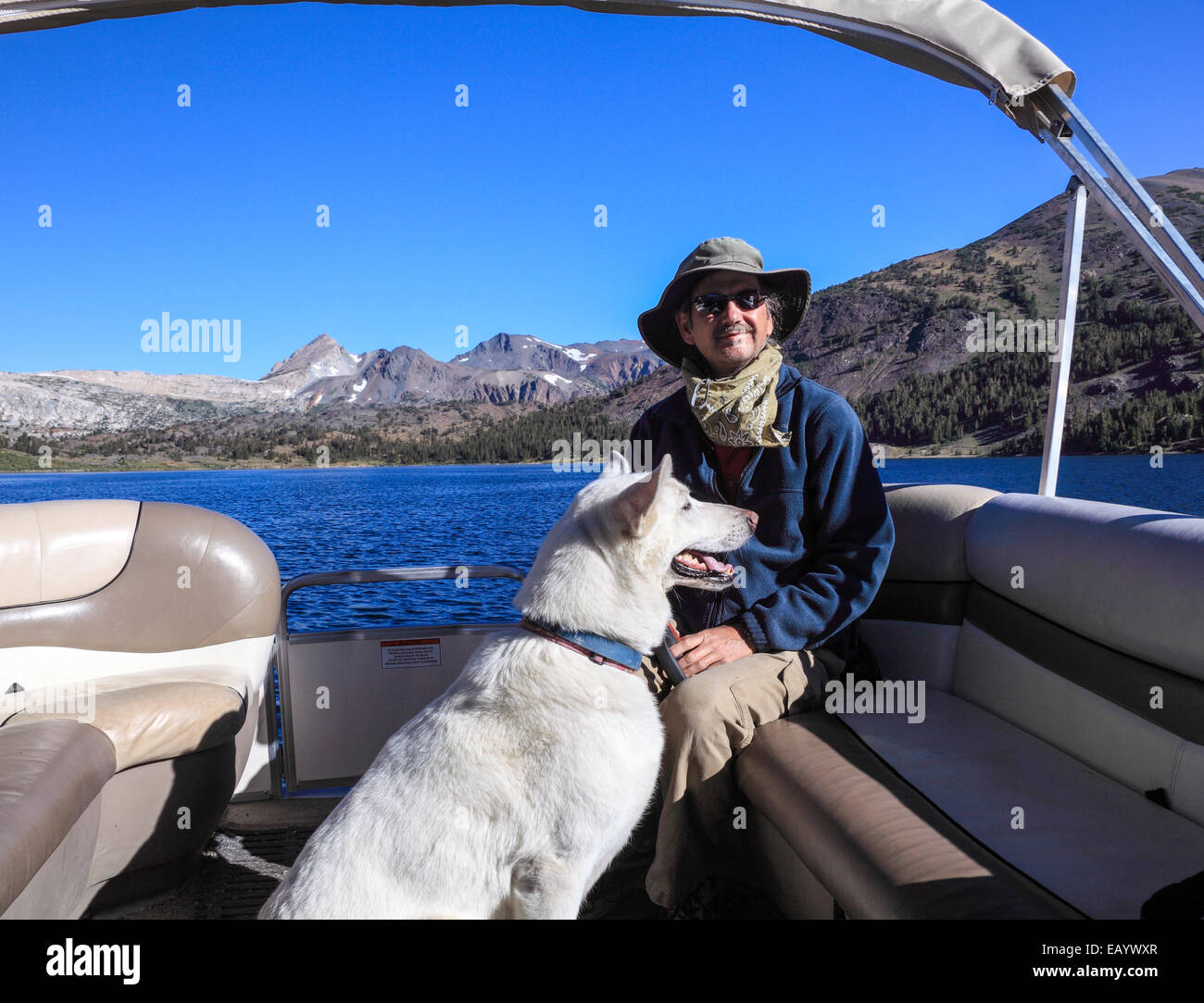 Uomo e cane in barca nel lago di borsette che trasporta gli escursionisti per e dal sentiero a 20 bacino dei Laghi Foto Stock