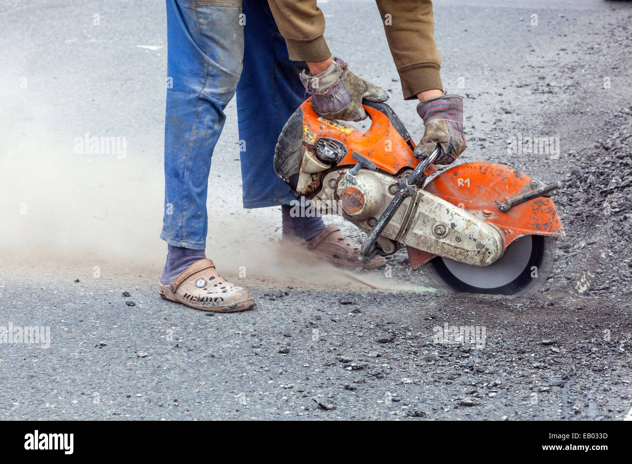 Un uomo lavora tagliare strada asfaltata con una fresa diamantata, nessun lavoro di protezione ingranaggio, Repubblica Ceca Foto Stock