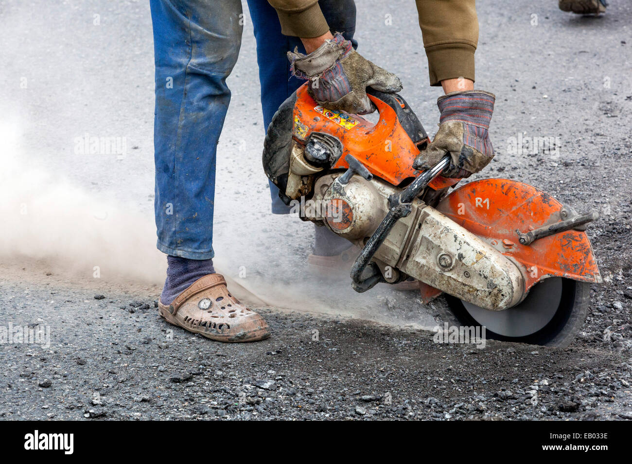 Un uomo lavora tagliare strada asfaltata con una fresa diamantata, nessun lavoro di protezione ingranaggio, Repubblica Ceca Foto Stock
