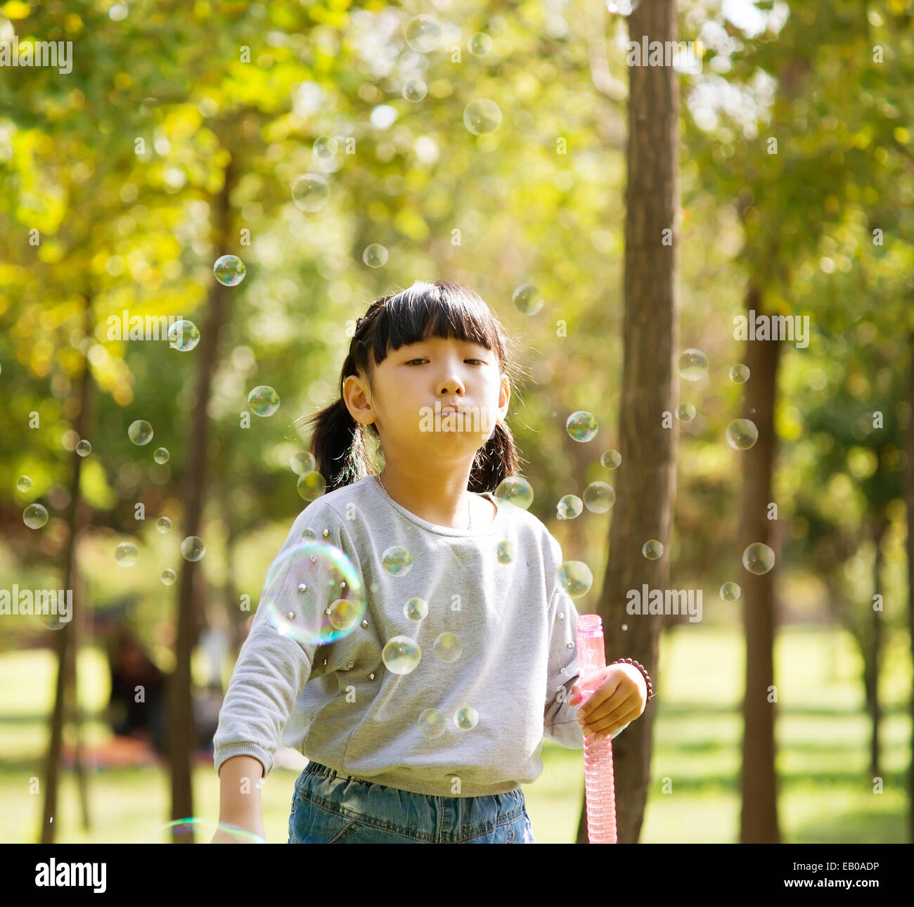 Ritratto di una bambina soffiando bolle di sapone al parco Foto Stock