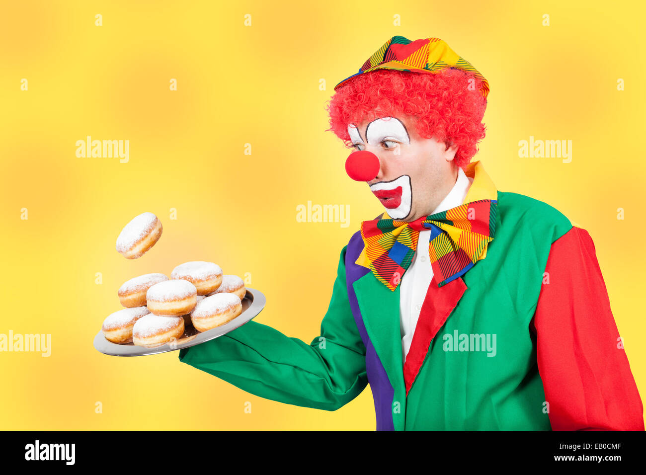 Clown con pancake sul vassoio su sfondo giallo Foto Stock