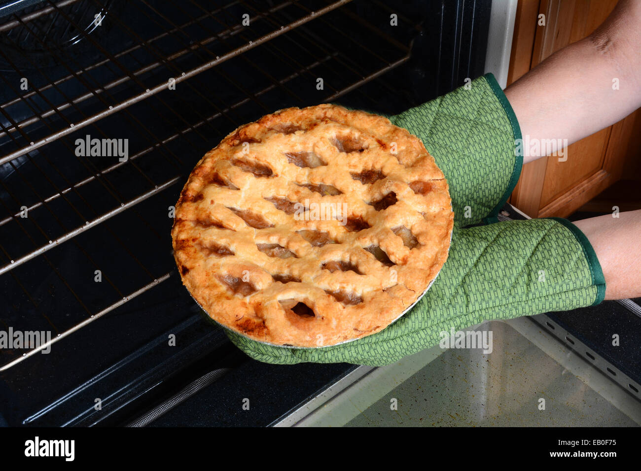 Primo piano di una donna prendendo una fresca mela cotta la torta dal forno. La torta di mele è un tradizionale American dessert per feste vacanze. Foto Stock