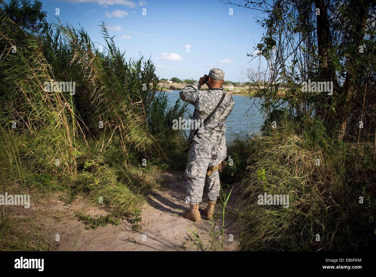 Un soldato dell'esercito Texas Guardia Nazionale osserva una sezione del Fiume Rio Grande lungo il confine Texas-Mexico a sostegno del funzionamento di sicurezza forte per aiutare a guardia del confine Settembre 11, 2014 in McAllen, Texas. Foto Stock