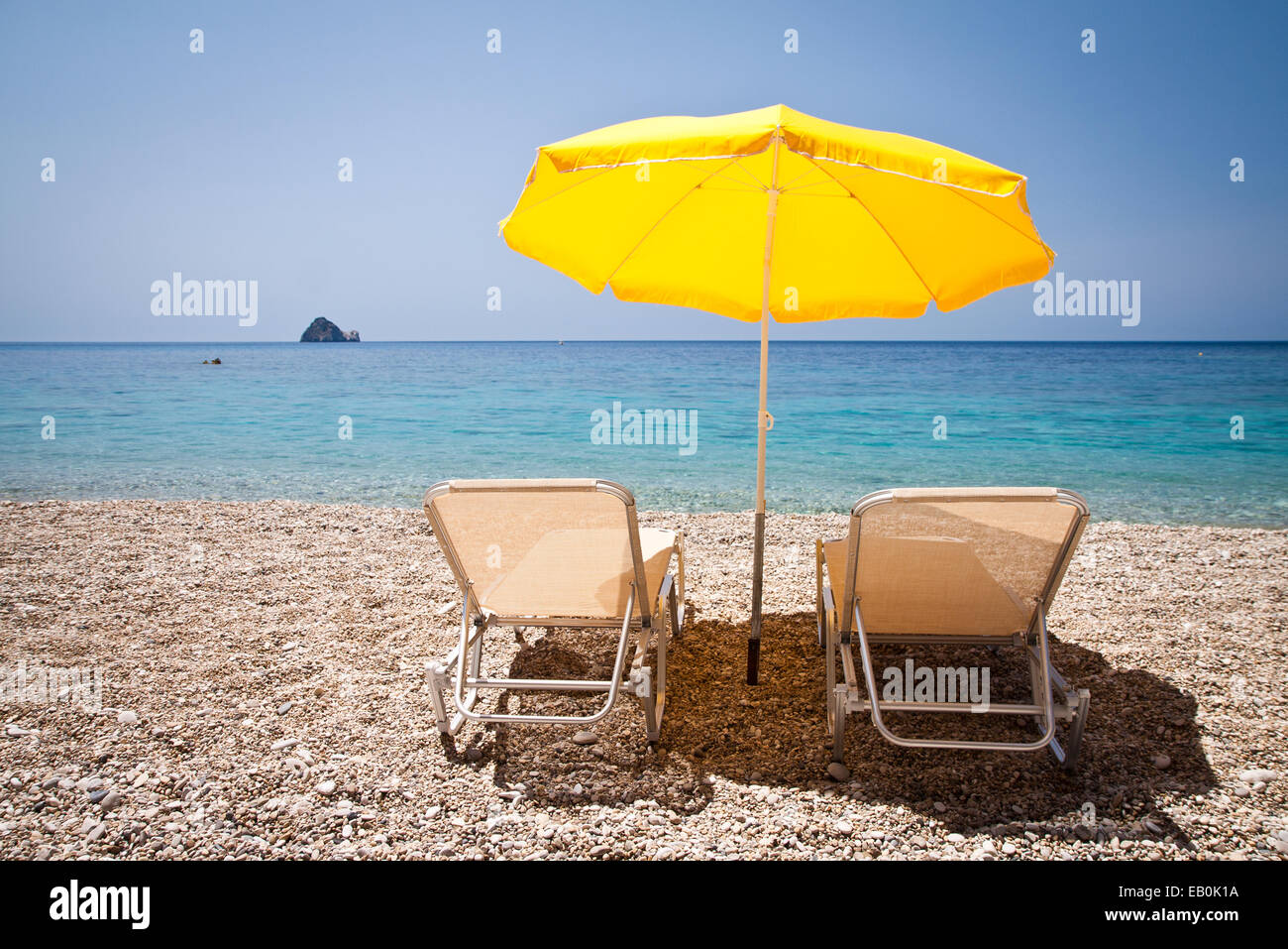 Sedie a sdraio e ombrellone in spiaggia Foto Stock