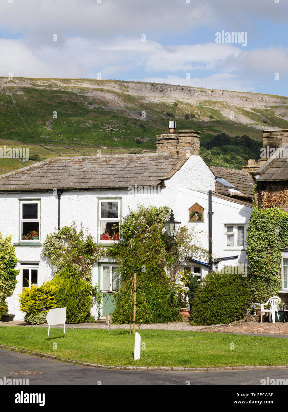 Un bianco cottage in Reeth, Yorkshire Dales con bordo Fremington dietro Foto Stock