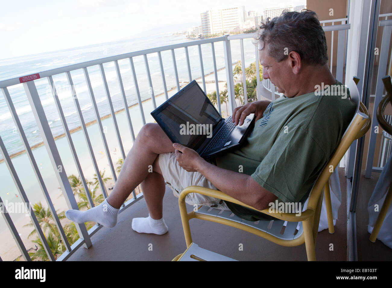 Hotel guest che naviga in internet sul balcone con vista oceano, Oahu, Hawaii Foto Stock