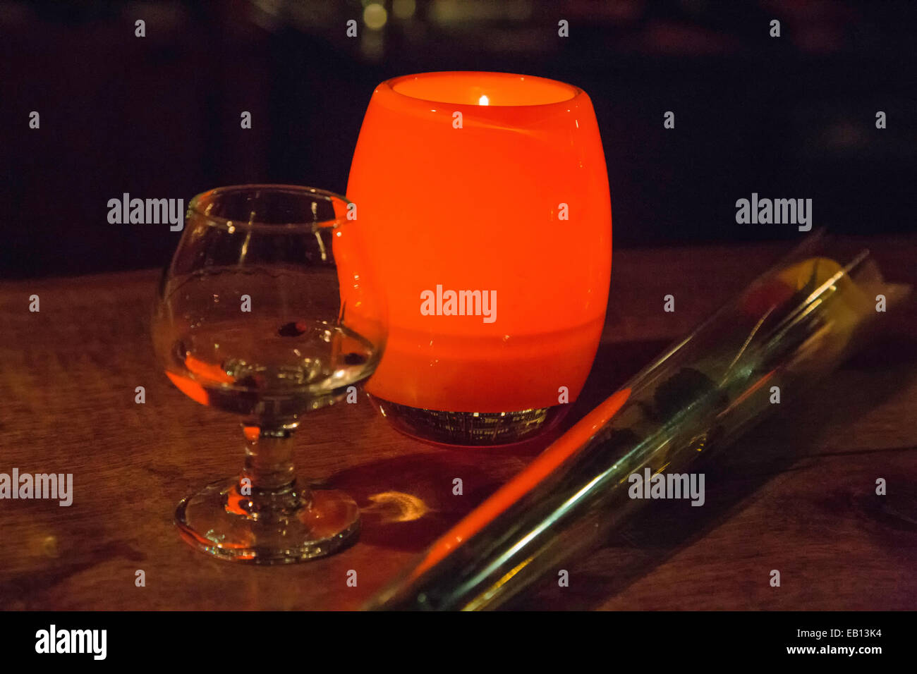 Un singolo bicchiere di liquore, una candela e rose su una barra a Seattle, Washington. Foto Stock