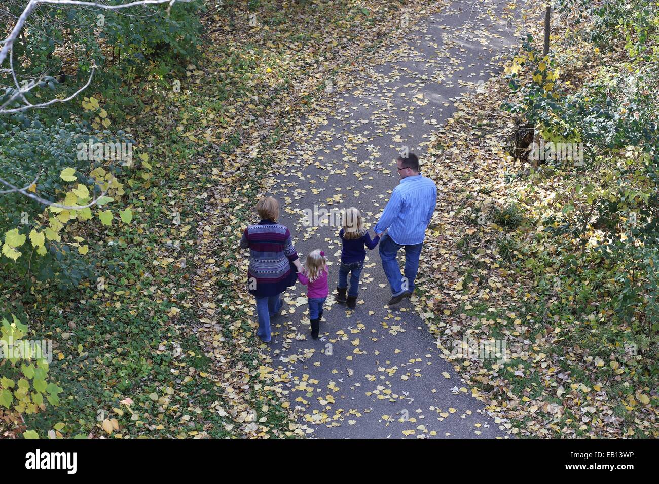 Una giovane famiglia a piedi su un percorso, come visto da sopra e da dietro. Foto Stock