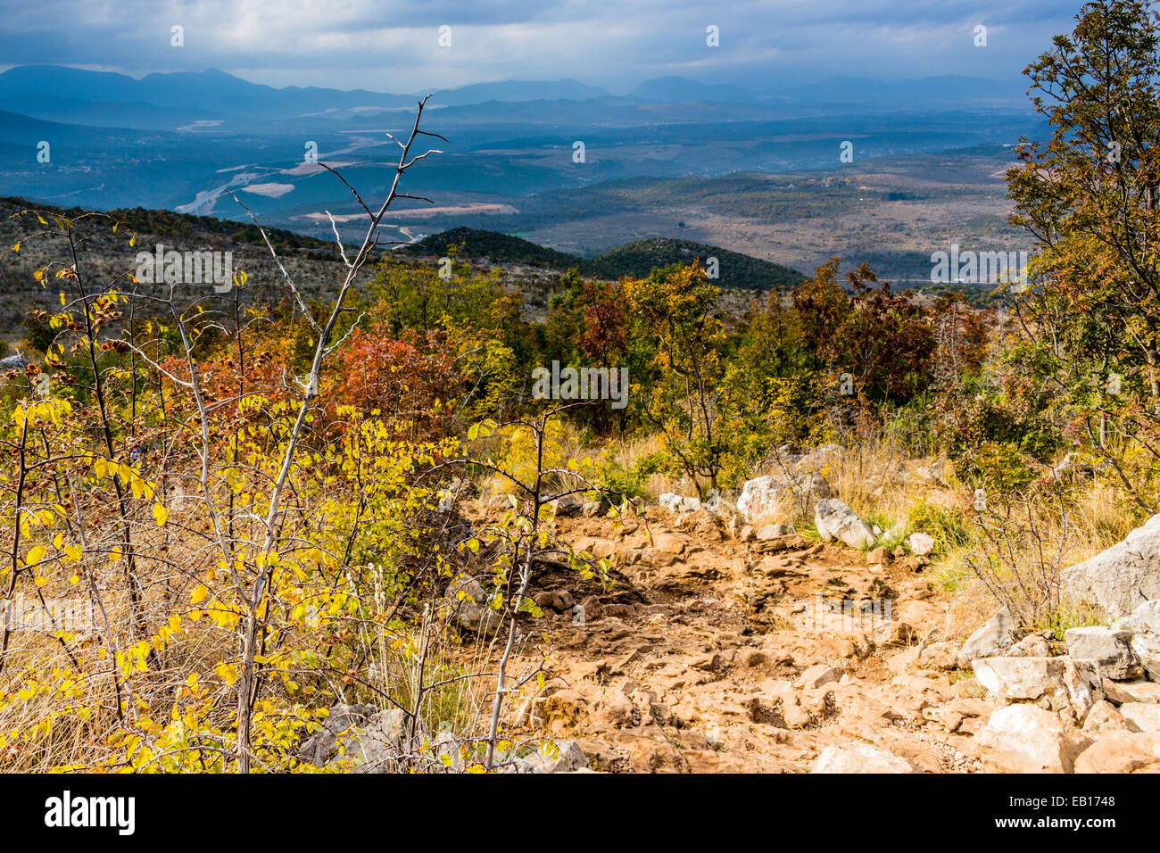 Vista autunnale del Krizevac (Cross) montagna a Medjugorje in Bosnia ed Erzegovina: marroncina alberi, erbe infestanti verdi, arancione e giallo di foglie e di rocce grigie Foto Stock