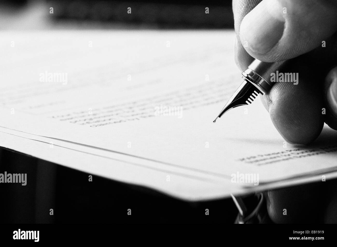 Una mano che tiene una penna stilografica e in procinto di firmare una lettera. Styling e piccole quantità di grani applicati. Foto Stock