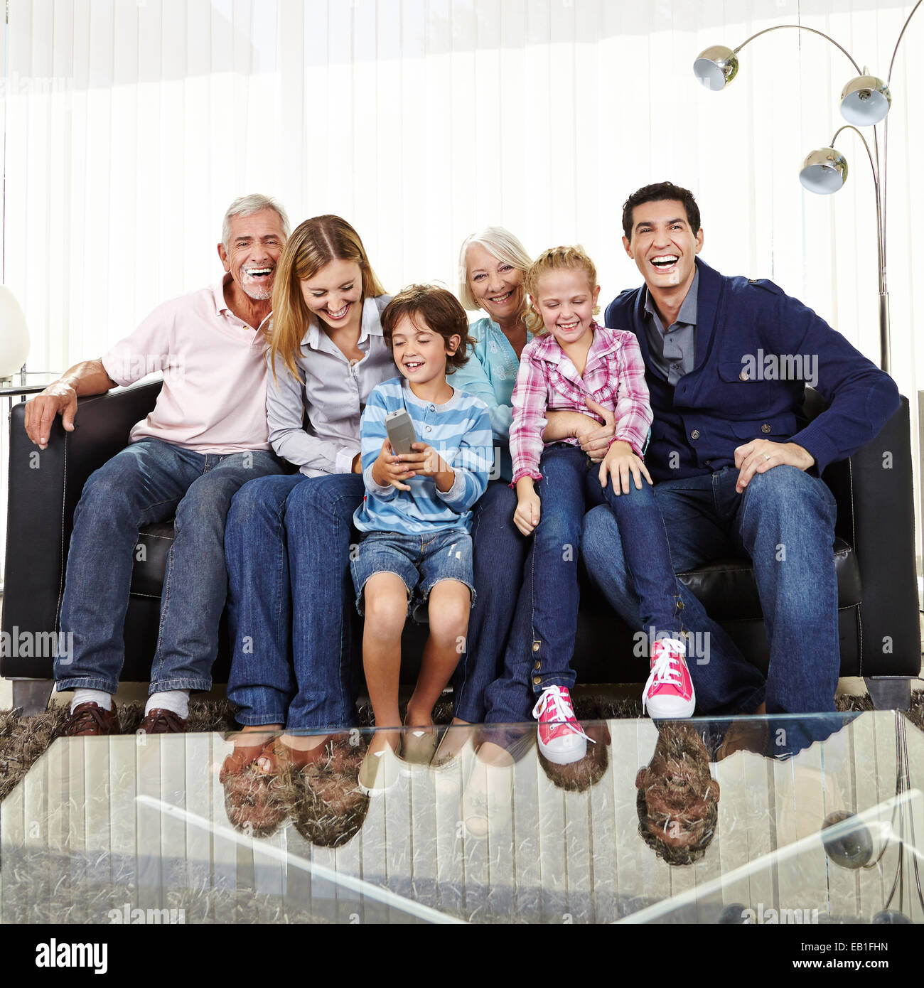 Felice famiglia grande sul divano guardando Smart TV con telecomando Foto Stock