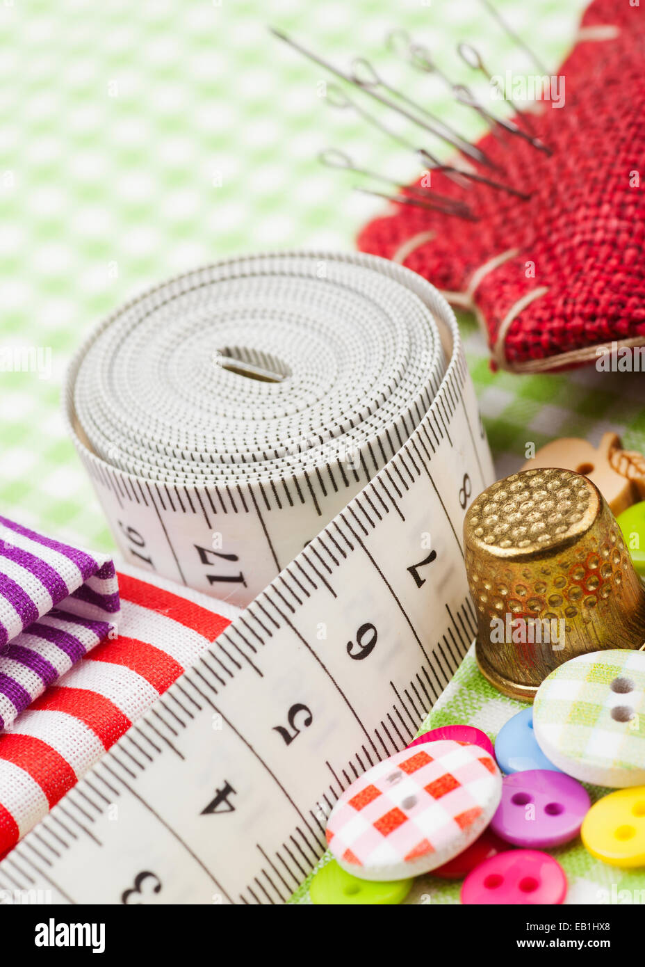 Elementi di cucitura: pulsanti, tessuti colorati, nastro di misurazione, pin cuscino, ditale Foto Stock