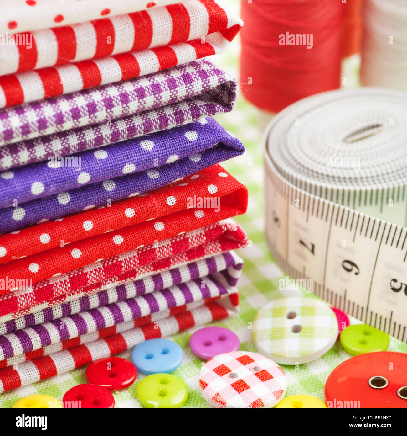 Elementi di cucitura: pulsanti, tessuti colorati, nastro di misurazione e rocchetto di filo Foto Stock