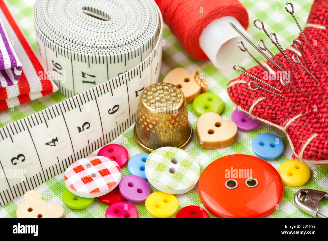Elementi di cucitura: pulsanti, tessuti colorati, nastro di misurazione, pin cuscino, ditale, rocchetto di filo Foto Stock