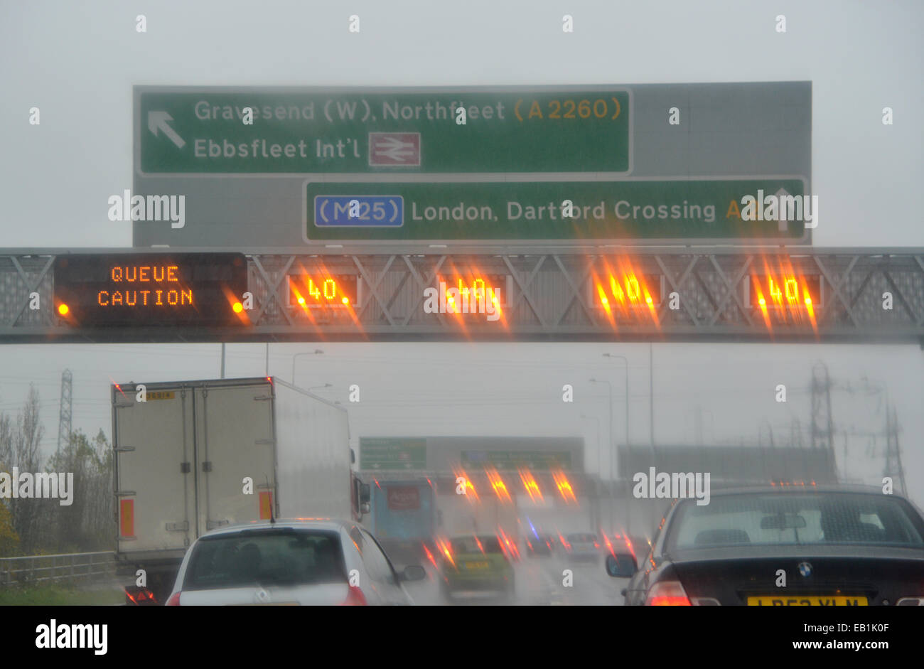 I limiti di velocità e di coda cartelli di avvertimento si accendono durante la fase di versamento pioggia sopra l'autostrada M2 NEL REGNO UNITO Foto Stock