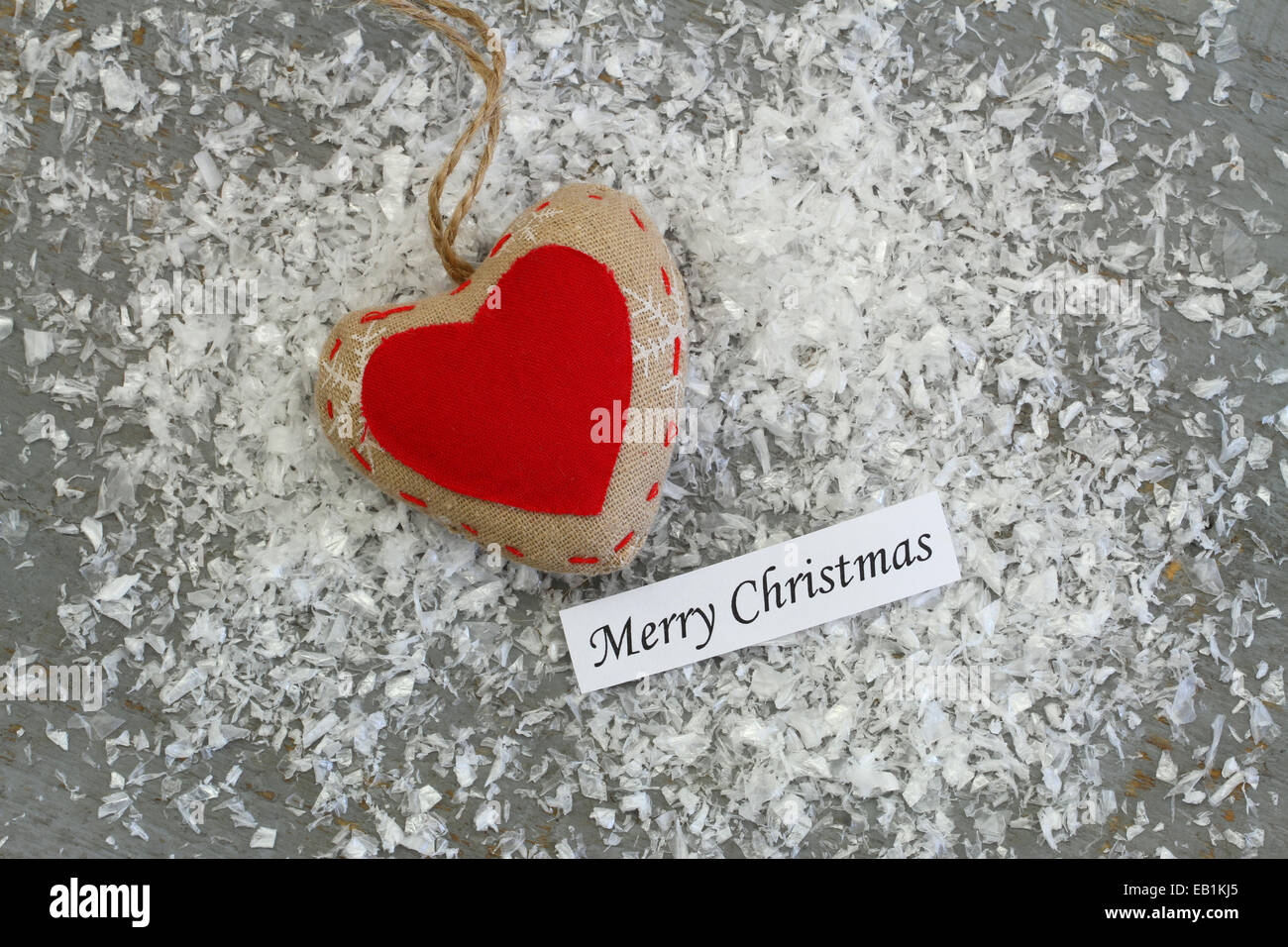 Merry Christmas card con tela rossa cuore sulla superficie nevosa Foto Stock