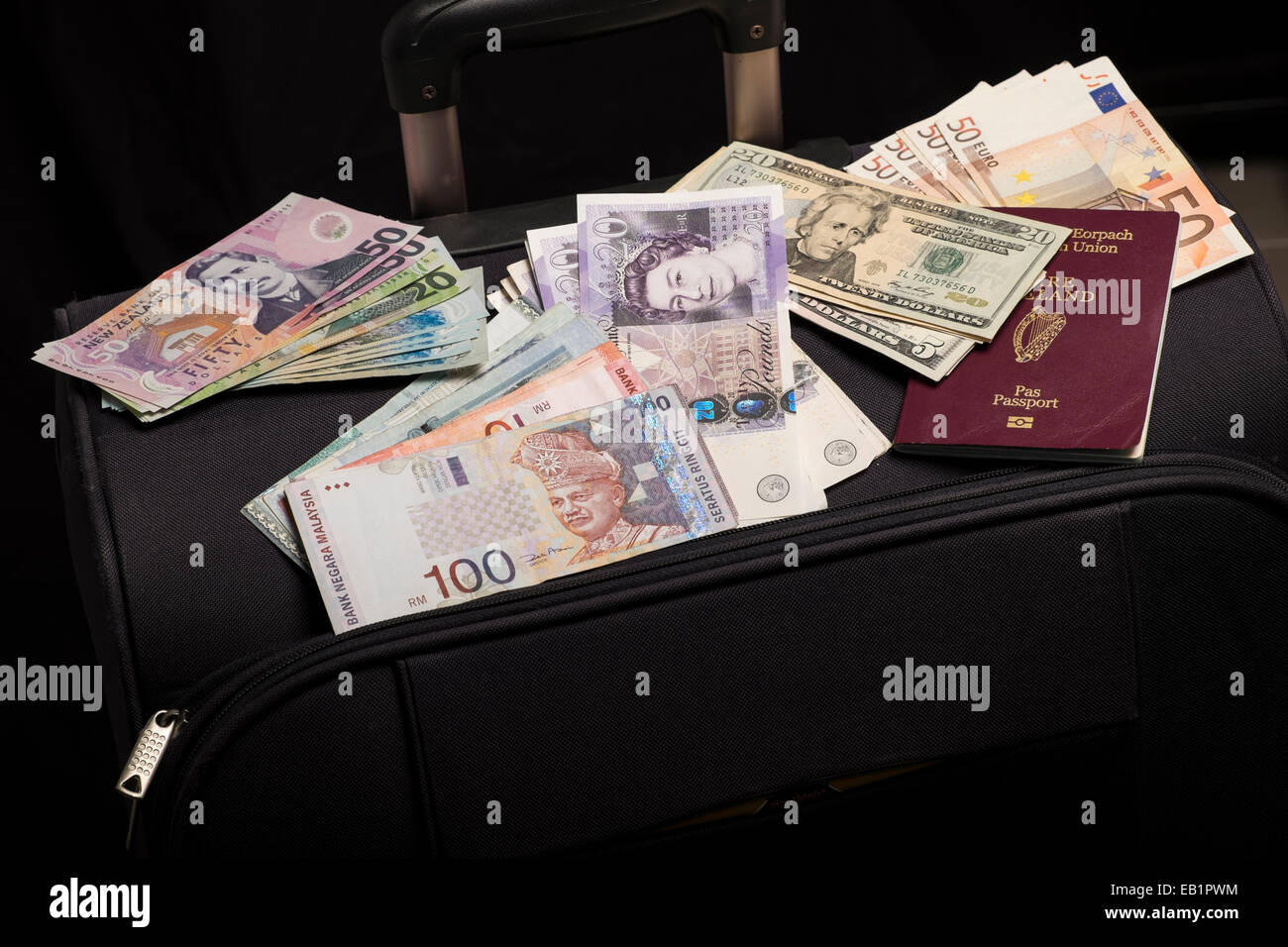Moneta note, dollaro US, dollaro neozelandese, Ringitts Malesi, sterline inglesi, euro e passaporto irlandese su una valigia Foto Stock