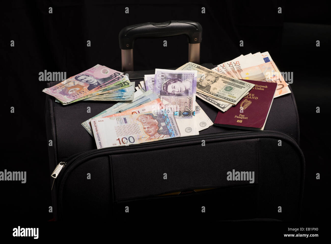 Moneta note, dollaro US, dollaro neozelandese, Ringitts Malesi, sterline inglesi, euro e passaporto irlandese su una valigia Foto Stock