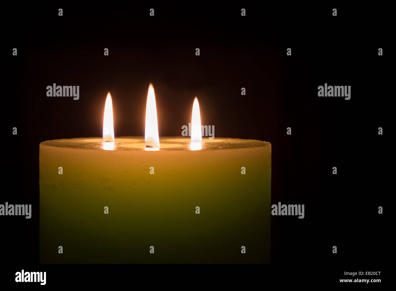 Candela con tre fiamme su sfondo nero con spazio di copia Foto Stock