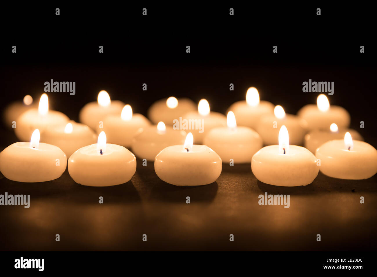Diverse candele bianche con il fuoco selettivo su sfondo nero Foto Stock