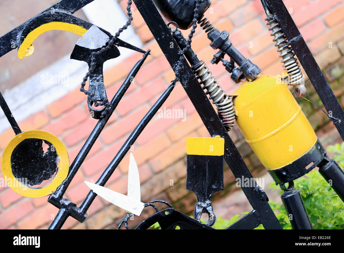 Nero e Giallo dipinto di parti di biciclette e vecchi utensili avvitata ad una porta metallica di un ristorante in una strada di Pokhara-Nepal. Foto Stock