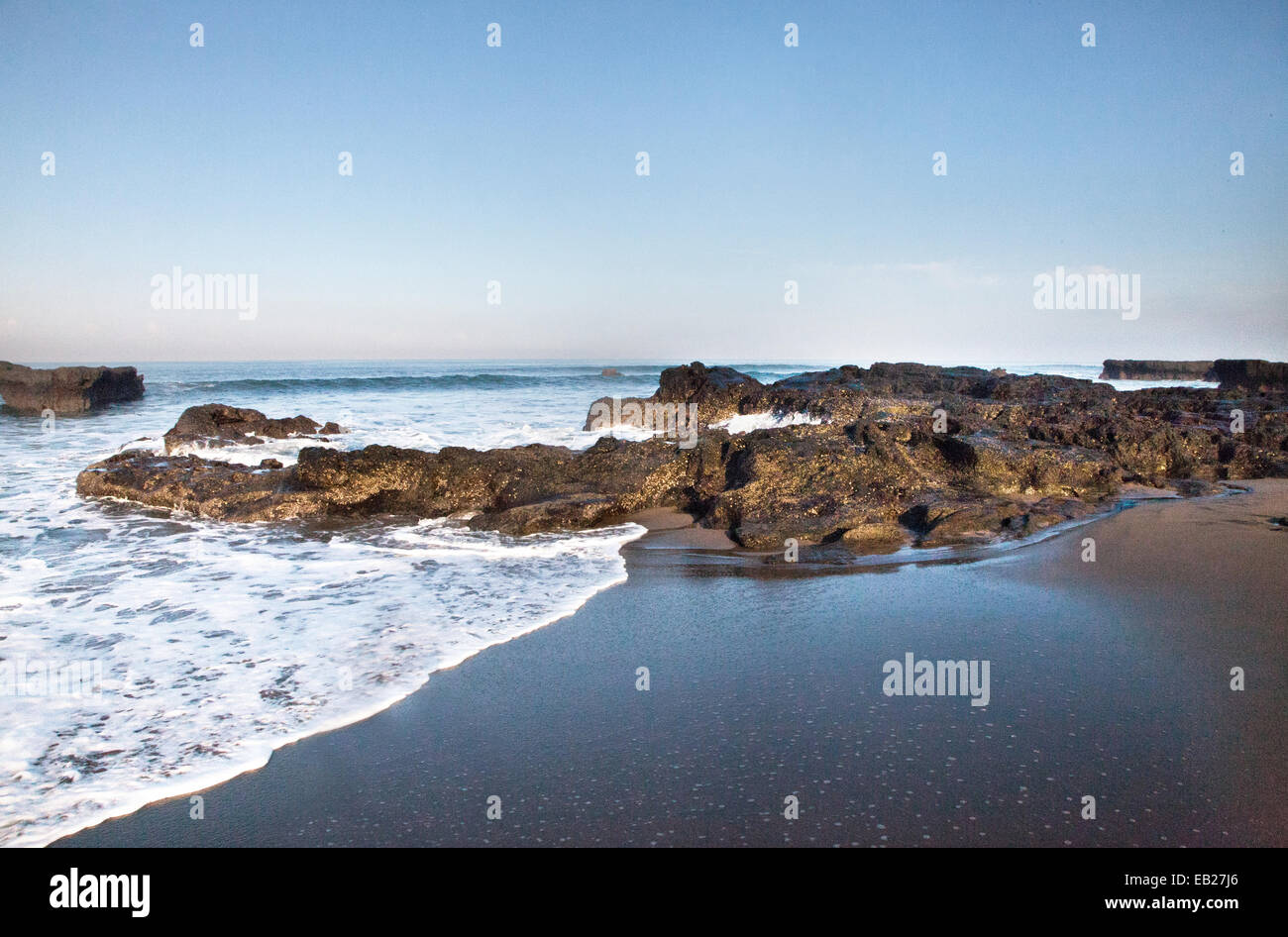 Bel mattino seascape immagine della marea sulla costa di bali a echo spiaggia come il surf giunchi sulle rocce sulla riva del mare. Foto Stock