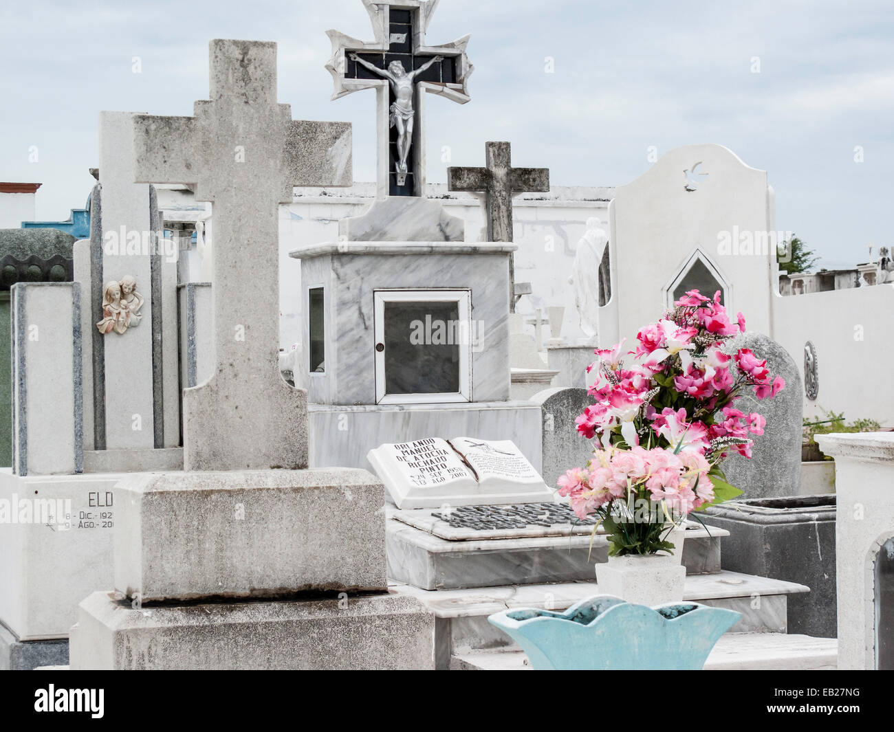 Tombe cristiane in marmo e pietra con croci e tomba offerta di fiori rosa brillante nel cimitero di Panteon de San Roman, Campeche, Messico. Foto Stock