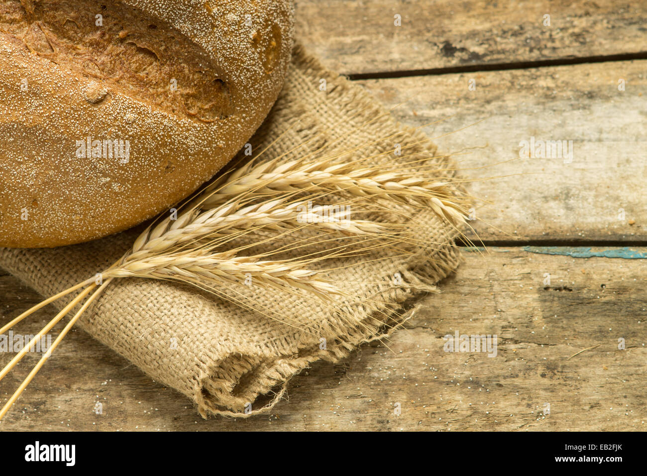 Filone di pane integrale con le orecchie su uno sfondo di legno Foto Stock