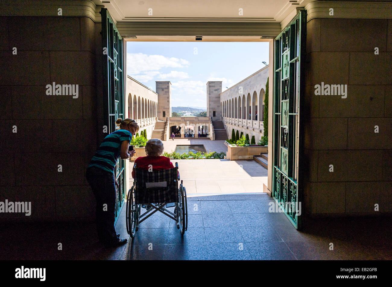 Una signora anziana che guardano sul cortile Memorial e il Memorial Pool dalla sala della memoria. Foto Stock