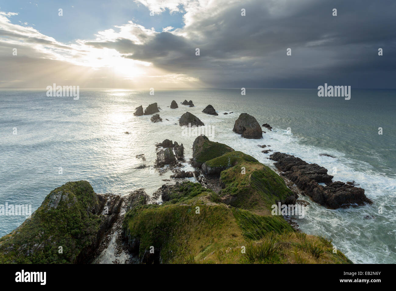 Scogliere che salgono dal Pacifico con un Rising Sun, al Nugget Point, Nugget Point, Ahuriri piana, Regione di Otago, Nuova Zelanda Foto Stock
