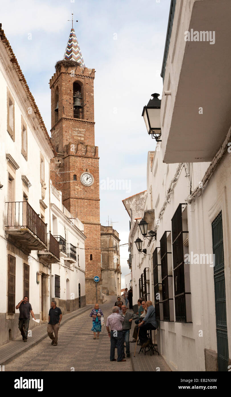 La chiesa di Nostra Signora dell'Assunzione e persone in village street, Aroche, Sierra de Aracena, provincia di Huelva, Spagna Foto Stock