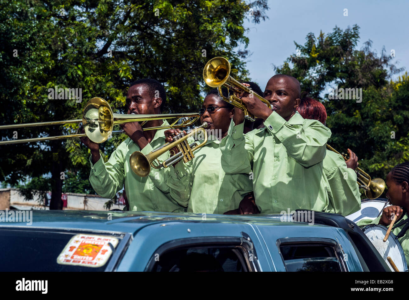 Una band suona musica per un corteo nuziale da un veicolo utilitario nella strada principale di un villaggio. Foto Stock