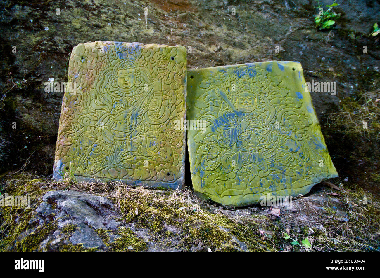 Il Lichen incrostati di tavolette di pietra in un monastero buddista con incisioni dei due bodhisattvas Foto Stock