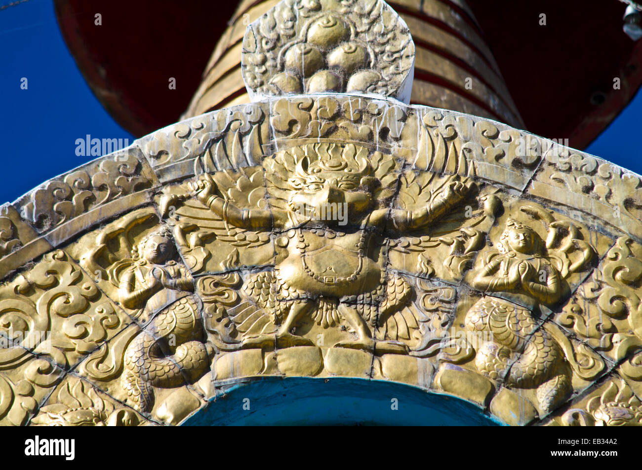 Un golden Garuda su un arco sotto una guglia dorata e le campane che riflettono la luce solare. Foto Stock