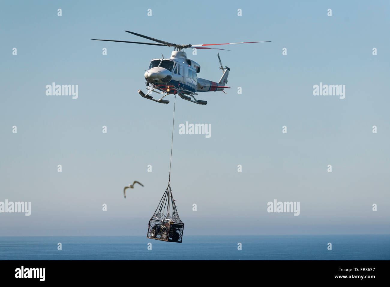 Atlantic Airways elicottero il trasporto di una moto quad, carico esterno il trasporto con un net, Mykines, Mykines, Isole Faerøer Foto Stock