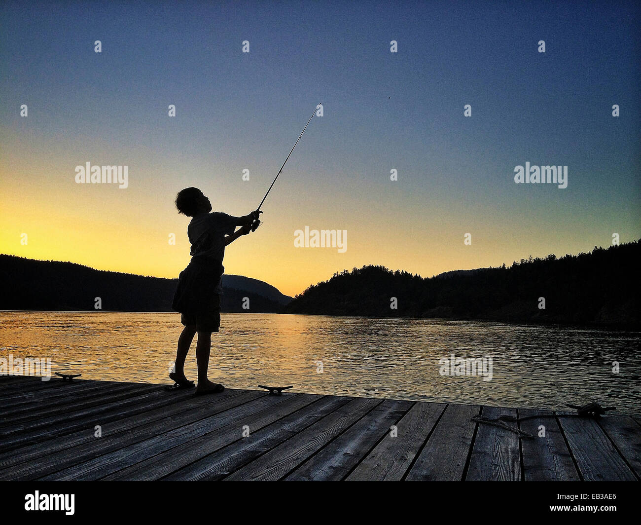 Ragazzo caucasico pesca sul dock a lago - Immagine stock catturata con smartphone Ragazzo caucasico pesca sul dock a lago - Immagine stock catturata con smartphone