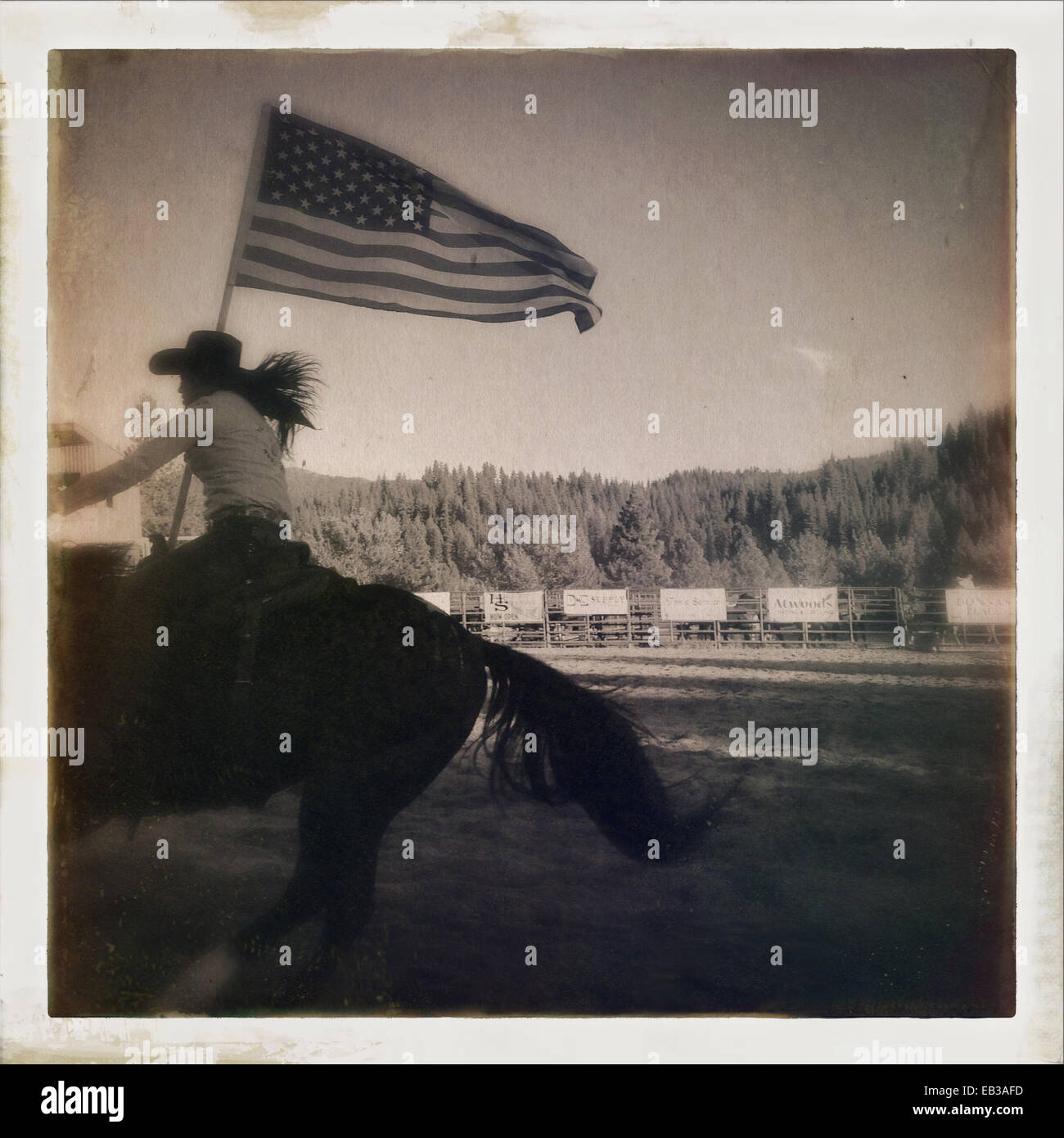 Cowgirl con bandiera americana di equitazione in rodeo - Immagine stock catturata con smartphone