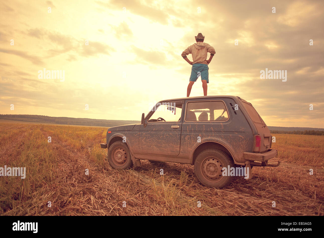 Mari uomo in piedi sul tetto del veicolo in campo rurale Foto Stock