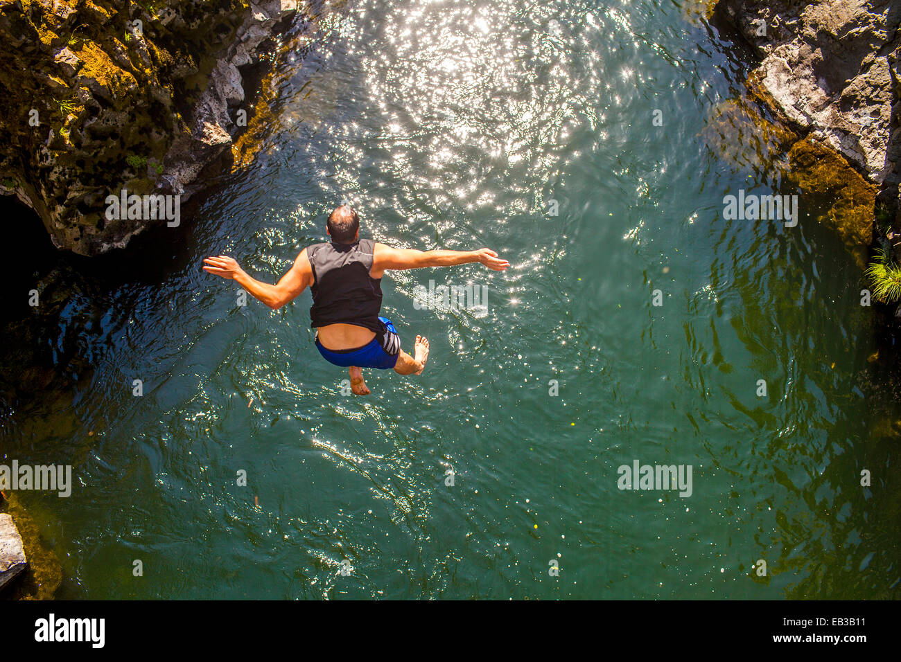 Uomo caucasico jumping Rocks off in ocean Foto Stock