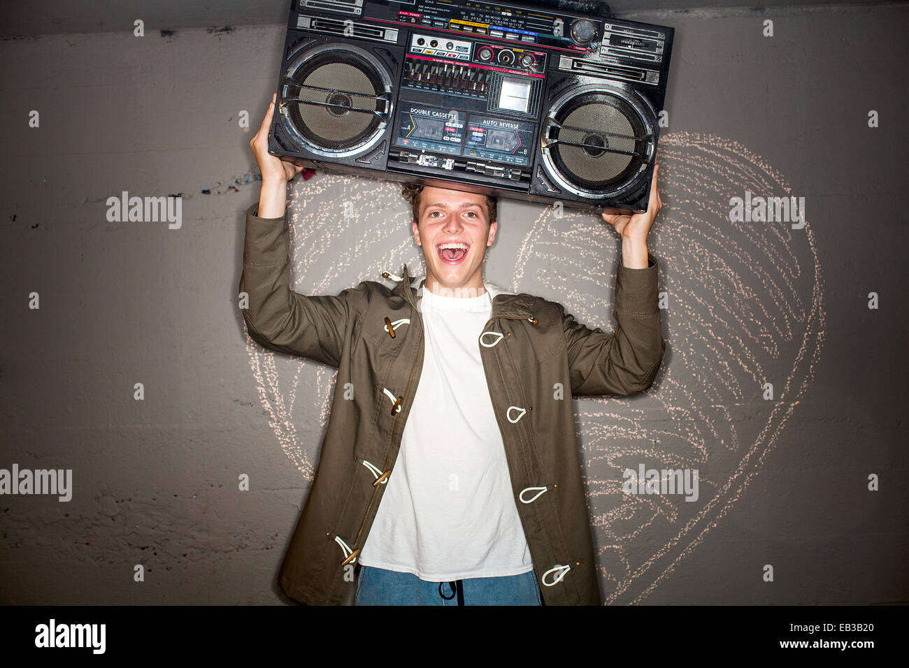 Uomo caucasico holding boom box vicino a Chalk cuore sulla parete Foto Stock