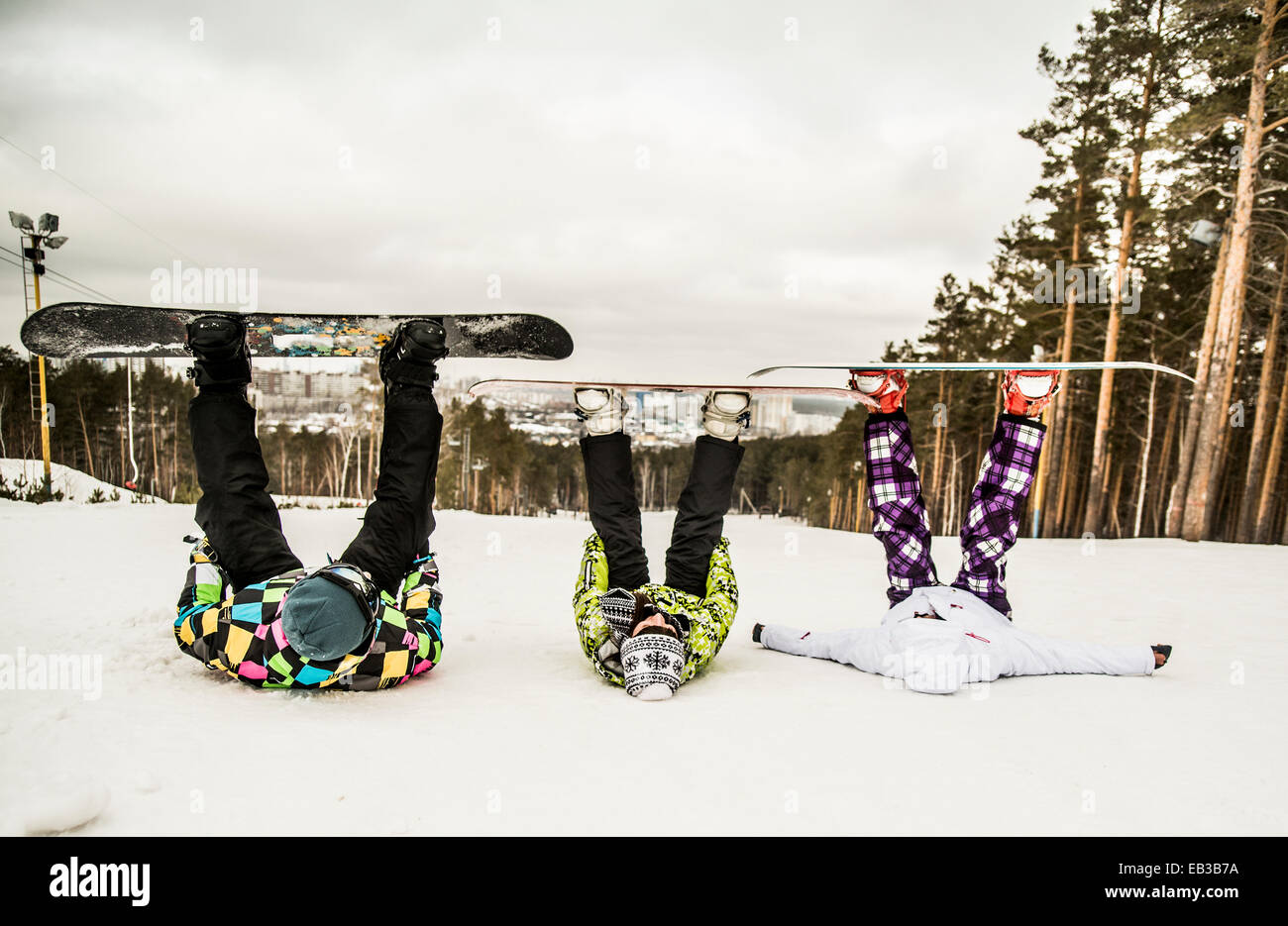Gli appassionati di snowboard caucasica recante nella neve con le gambe sollevate Foto Stock