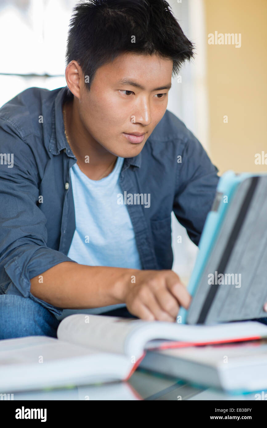Uomo coreano studiare con tavoletta digitale Foto Stock