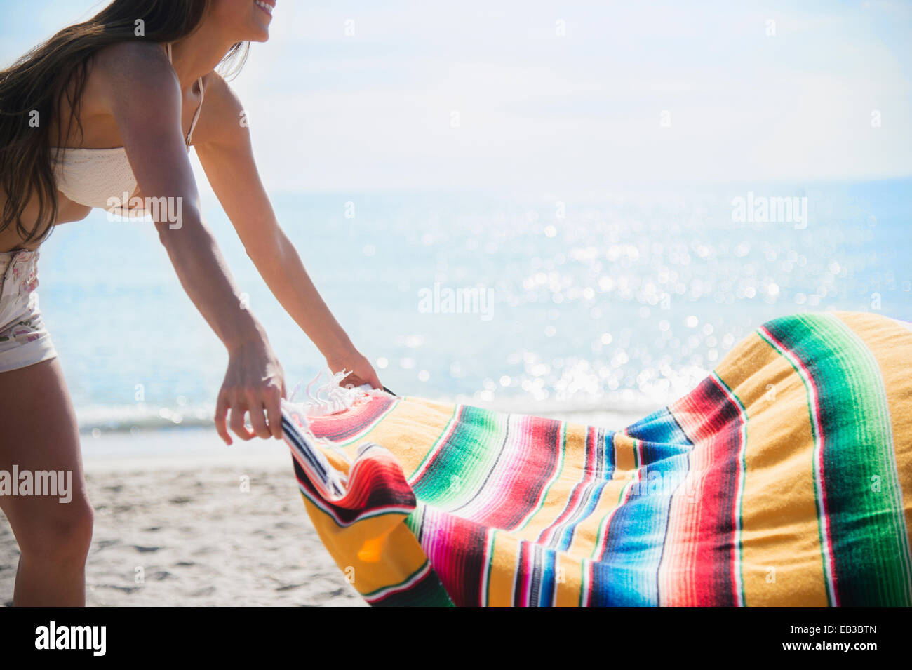 La donna caucasica coperta di spandimento sulla spiaggia Foto Stock