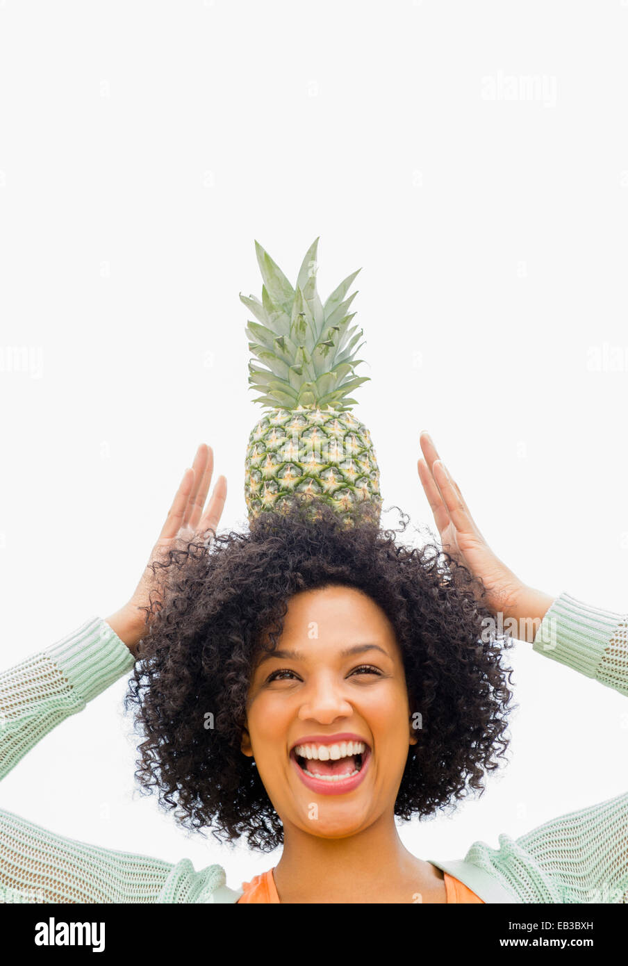 Donna sorridente equilibratura di ananas sulla testa Foto Stock