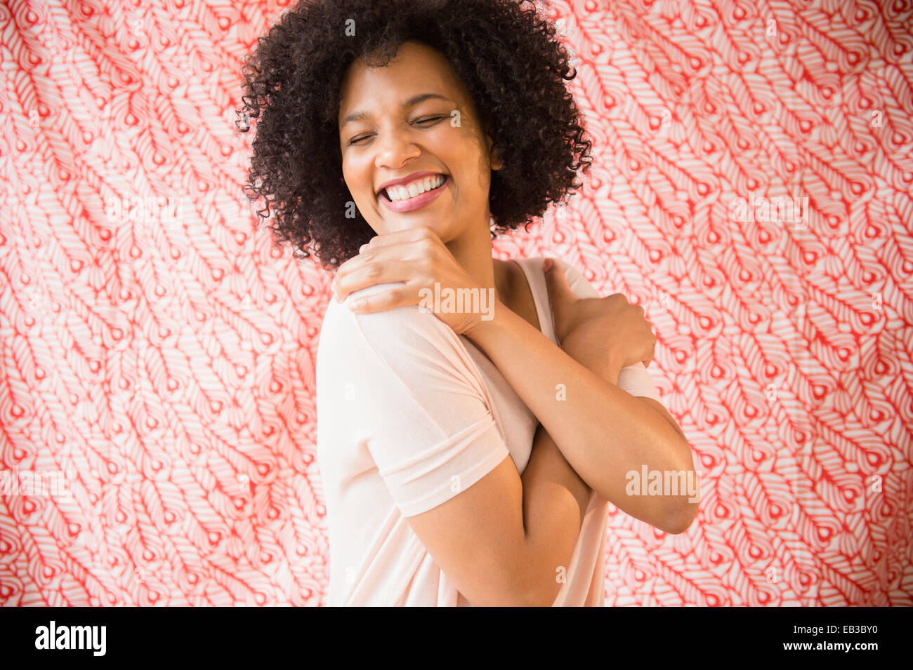 Donna sorridente abbracciando se stessa Foto Stock