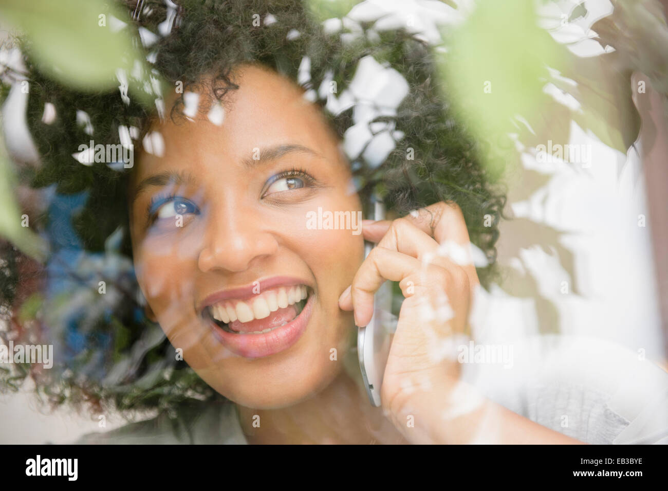Donna sorridente parlando al cellulare vicino a finestra Foto Stock