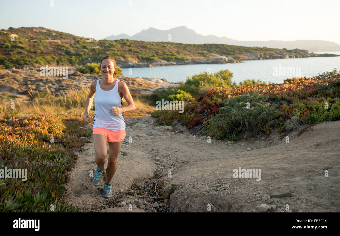 Donna che fa jogging lungo un sentiero costiero, Corsica, Francia Foto Stock