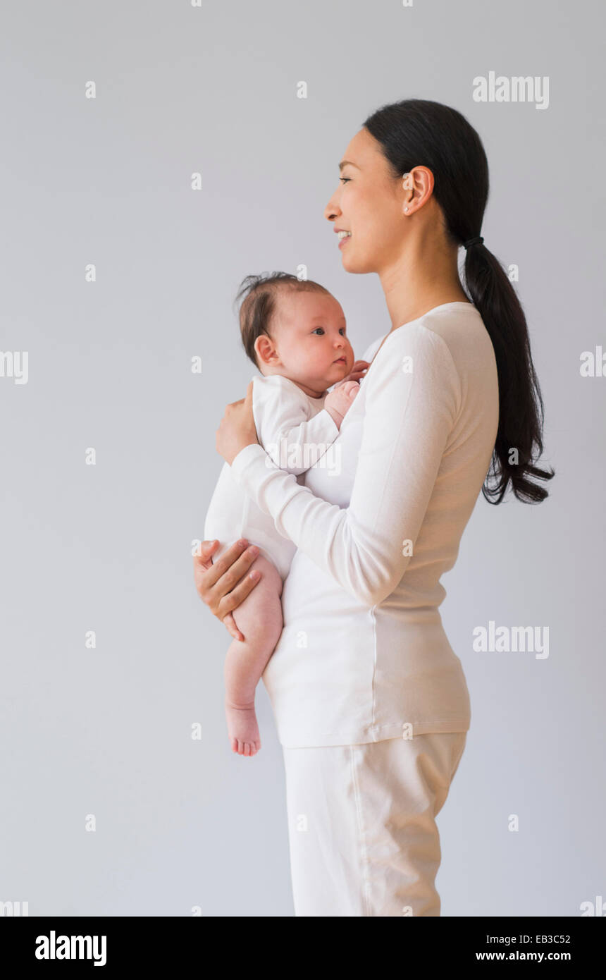 Profilo di Asian madre holding baby Foto Stock